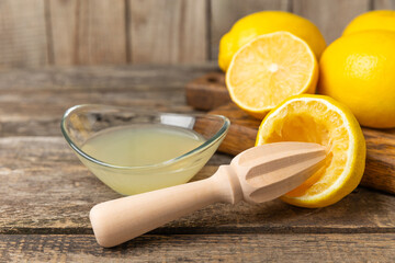 Lemon juice. Fresh lemon juice in a bowl. Ripe citrus, mint, fruit, and a juicer on the table. Vitamin C. Lemon water. Ingredient for baking or salad dressing. Space for text. Copy space.