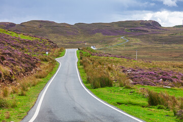 Winding rural road through heather moorland Isle of Skye Scotland