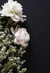 Delicate white flowers and buds arranged beautifully on a dark surface
