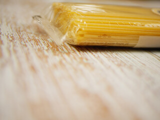 Packaged dry spaghetti lying on rustic wooden surface showing unopened pasta texture and product details for cooking themes, ingredient presentations, and clean food branding, pro photo