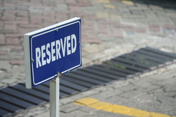 Blue reserved parking sign placed on an urban street pavement. Clear typography with shallow depth of field, suitable for concepts of exclusivity, priority, reservation, and access control.