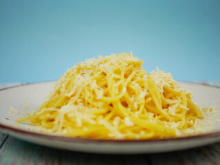 Plate of spaghetti with grated parmesan cheese on blue and white background, vertical Italian pasta image for restaurant posters, menus and social media content. Pro Photo