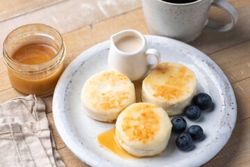 Cottage cheese fritters, syrniki served with honey and fresh blueberries