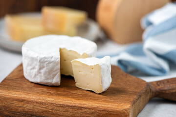 Camembert, brie cheese on wooden board. Slice cut out. Closeup view french cheese