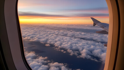 Obraz premium View from airplane window showing wing above soft clouds at sunset, colorful sky