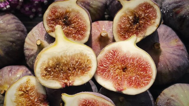 Delicate fresh ripe figs with flowers on wooden table. Ficus carica. Beautiful sweet seasonal fruits, vegan food. Top view. Dolly slider shot. 