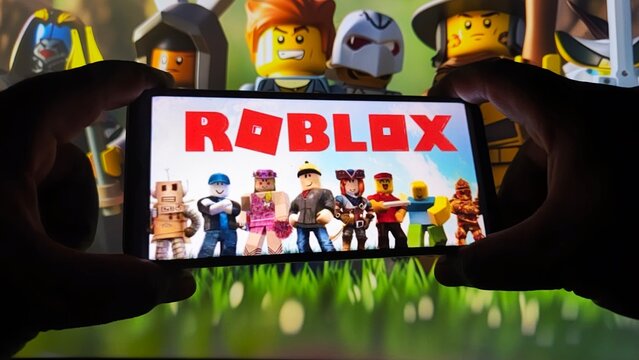 Hands holding smartphone with Roblox game on screen surrounded by characters