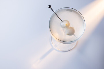 Gibson martini on a reflective white surface with high contrast lighting and contrasting tones.