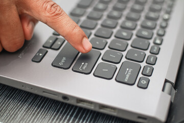 Close Up Of A Finger Pressing The Enter Key On A Silver Laptop Keyboard With Black Keys