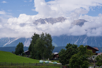 Scenic mountain countryside with open meadows, forested slopes and small rural homes. Calm natural environment, fresh air, travel destination and outdoor lifestyle concept.