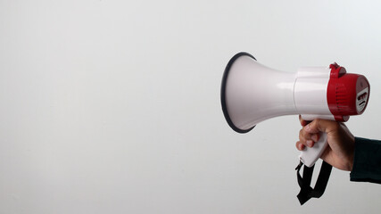 Hand holding a red and white megaphone. Isolated on white background. Concept of announcement, communication, alert, protest, or public speaking.