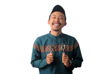 Happy Asian Muslim man wearing a black peci cap (songkok), looking to the side toward empty copy space with a thoughtful expression while fasting during Ramadan, Isolated on a white background