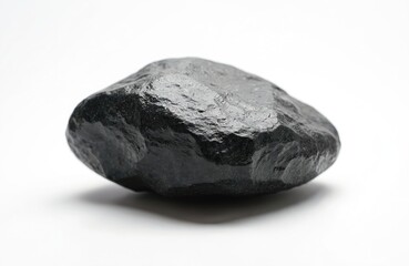 Fototapeta premium Smooth black hematite stone rests on white background. This mineral rock has a shiny surface and irregular shape. Used in jewelry making and industry.