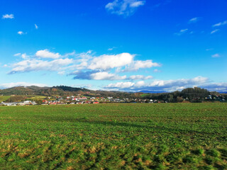 Green field and rural village by blue sky in winter Slovakia
