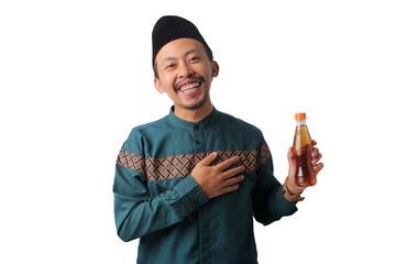 Asian Muslim man in green traditional outfit holding a bottle of tea, gesturing "wait a minute" as he eagerly waits for iftar (the time to break his fast) during Ramadan. Isolated on white background