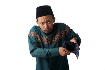 Sad young Asian Muslim man holding an empty wallet toward the camera with a disappointed expression, representing financial difficulty during Ramadan before Eid Mubarak. Isolated on a white background