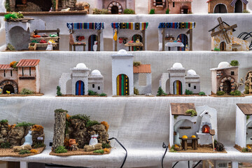 Handcrafted miniature houses and landscape elements for traditional Christmas nativity scenes at a market.