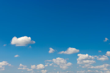 Clear blue sky with scattered cumulus clouds in peaceful daylight atmosphere