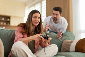 Woman ignoring upset boyfriend while playing video games