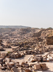 industrial landscape of mining quarry with excavator and granite marble blocks in Aravalli range