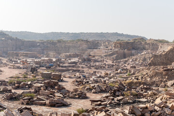 stone quarrying industry with heavy machinery in desert environment in Aravalli range