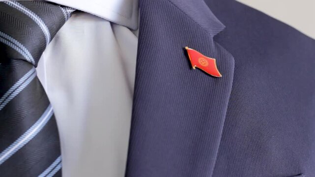 Businessman attaching the kyrgyzstan flag lapel pin to his suit