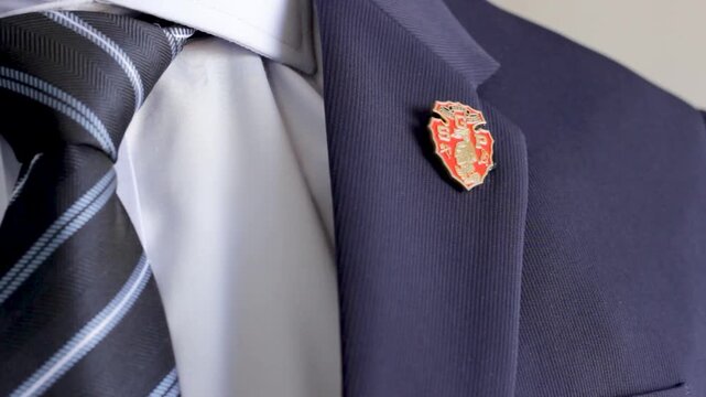 Graduate adjusting his suit jacket lapel with a south grand prairie pin