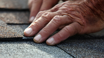 Ultra-realistic close-up of hands checking shingle alignment before final nailing