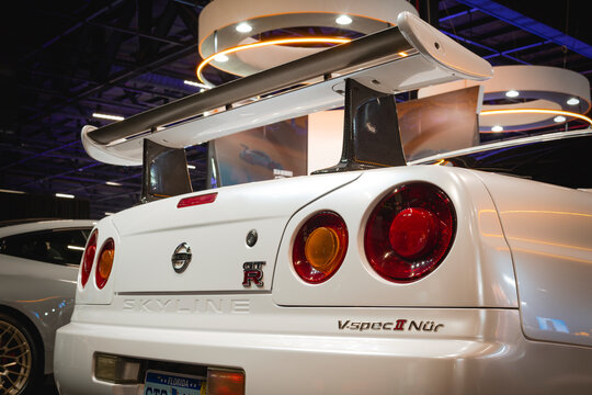 Rear view of the Nissan Skyline GT-R V-Spec II Nur, showcasing a sporty rear wing, circular taillights, and classic finish on display.