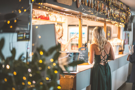 Woman in a green dress at a bar, waiting to order a drink