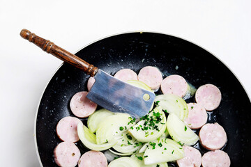 Sliced ​​sausage and onion in a pan while frying.