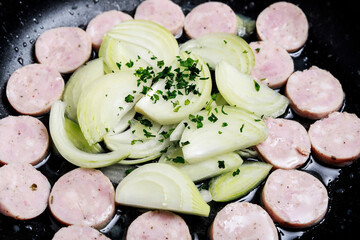Sliced ​​sausage and onion in a pan while frying.