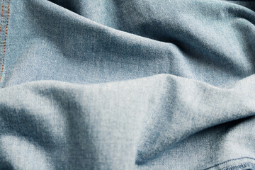 Dramatic lighting on denim fabric. Background, wallpaper.