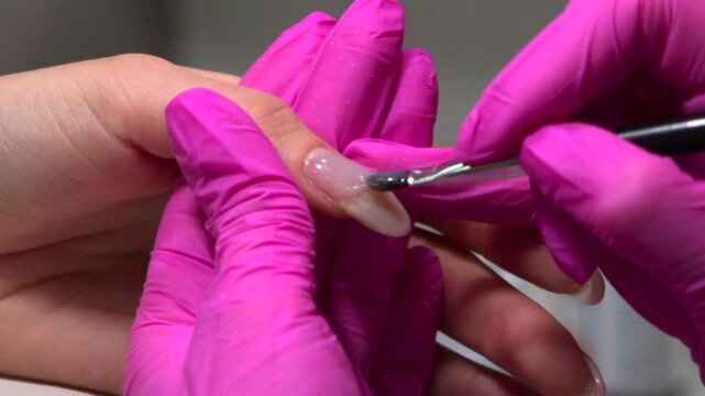 Closeup Acrylic Nail Sculpting With Brush And Pink Gloves Applying Builder Material For Extension. Media
