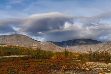 A Picturesque Mountain Valley Under a Stormy Sky with Autumn Colors and a Rare Forest Against a Mountainous Landscape