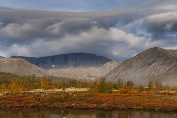 A Picturesque Mountain Valley Under a Stormy Sky with Autumn Colors and a Rare Forest Against a Mountainous Landscape