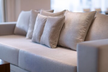 Contemporary sofa with textured cushions in neutral tones. Close-up of elegant living room furniture. Modern interior design concept with blurred background