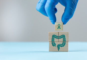 A doctor's hand arranges wooden cubes with a colon icon. Concept of colon health awareness, colorectal cancer prevention, early detection, timely treatment, and comprehensive gastrointestinal care.
