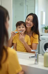 Ingelijste posters Tandarts Mother helps son brush teeth in bathroom. Happy family bonding, teaching oral hygiene with toothbrush and paste. Little boy smiles, woman cares for his dental health.  © Vadym
