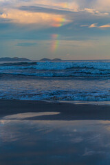 ao fundo um arco-&iacute;ris na costa de Bombinhas Mariscal  e o p&ocirc;r-do-sol na Praia Palmas do Arvoredo cidade de Governador Celso Ramos Santa Catarina Brasil regi&atilde;o da Grande Florianopolis 