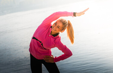  Fitness female athlete relaxing on beach doing a warm-up