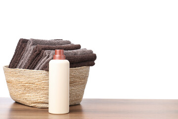 Naklejka premium Laundry basket with towels and bottle of detergent on wooden table against white background