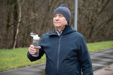Athlete and sporty caucasian man drinking water from bottle at public park after workout. Outdoors. Water balance. Young Man Training Outdoors