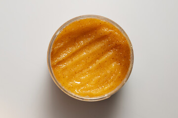 Yellow body scrub on a white background. Concept of cleansing and exfoliating skin.