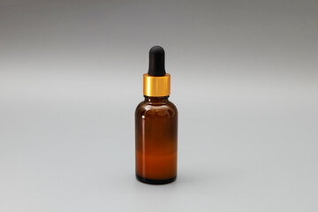 glass bottle with skin serum or other substance on a gray background