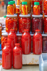 Pickled Peppers in Mason Jars and Bottles of Tomato Juice at Farmers Market Winter Food Preservation