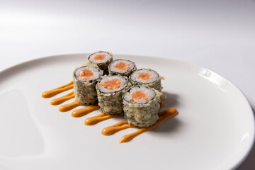 Tempura sushi rolls with crab filling served on a white plate with wasabi, pickled ginger