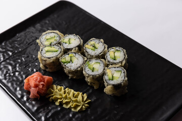 Salmon skin sushi roll served on a black stone, top view