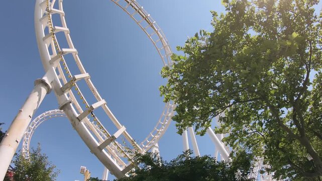 Thrilling roller coaster surrounded by greenery on a sunny day in the amusement park