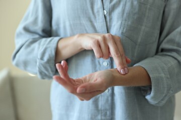 Woman checking her pulse with fingers indoors, closeup
